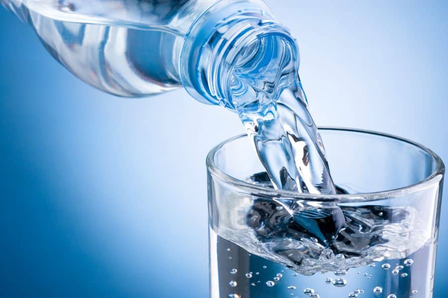 A bottle pour water into a glass cup